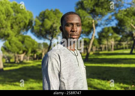 Ritratto di un giovane africano senegalese che indossa abiti tradizionali in un parco, che rappresenta la cultura senegalese e le tradizioni musulmane Foto Stock
