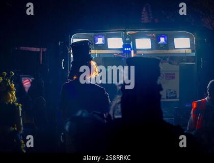Glastonbury, Regno Unito - 16 novembre 2024: Artisti del Carnevale in costumi, cappelli e parrucche, sagomati contro luci luminose rivolte lontano dalla telecamera Foto Stock