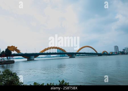 Il Dragon Bridge di da Nang, Vietnam, presenta un design dorato a forma di drago sul fiume Han, che rappresenta la forza e l'orgoglio culturale vietnamita. Foto Stock