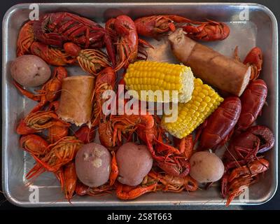 Un granchio bollito di circa 2,5 kg viene mostrato su un vassoio di metallo, servito insieme a patate, mais sulla pancetta e salsiccia, come parte della cucina cajun di New Orleans. Foto Stock