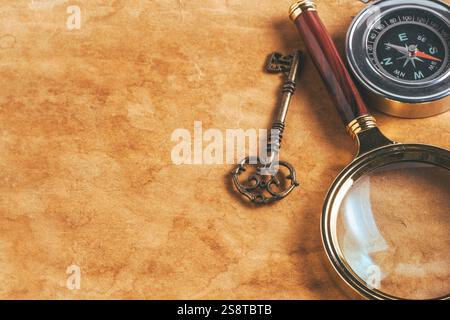 Lente d'ingrandimento vintage, bussola e chiave su sfondo di carta vecchia Foto Stock
