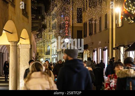 Lugano, Svizzera - 22 dicembre 2024: Una via festosa con luci natalizie e persone che si godono la notte in centro Foto Stock
