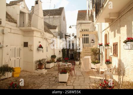 Pittoresco cortile con piccola area salotto e piante in vaso nel centro storico di noci, Italia Foto Stock