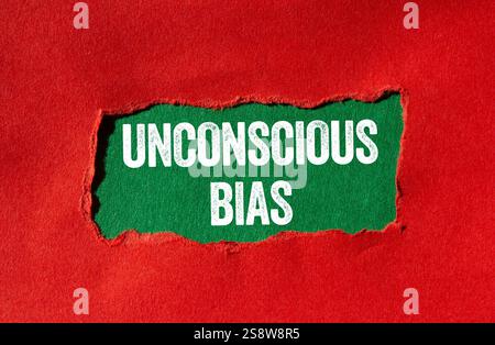 Messaggio di bias inconscio scritto su carta strappata rossa su sfondo verde. Simbolo di pregiudizio inconscio concettuale. Copia spazio. Foto Stock