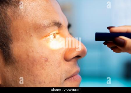 Optometrista che esegue un test di visione in un moderno ufficio clinico. Paziente indiano sottoposto a un esame oculistico, ottico che utilizza strumenti diagnostici per la correzione della vista alla consultazione. Primo piano. Foto Stock