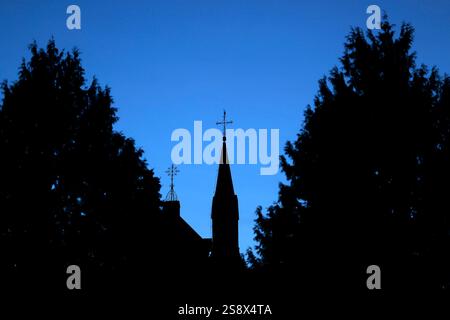Ein Kreuz mit Wetterhahn steht auf dem Dach einer Kirche vor Abendhimmel. Der Kirchenaustritt ist die vom Bürger auf eigenen Wunsch veranlasste Beendigung der staatlich registrierten Mitgliedschaft in einer Kirche. Themenbild, Symbolbild Frechen, 23.01.2025 NRW Deutschland *** Una croce con un rubinetto si erge sul tetto di una chiesa contro il cielo serale lasciando la chiesa è la fine dell'appartenenza statale a una chiesa su richiesta dei cittadini immagine a tema, immagine simbolica Frechen, 23 01 2025 NRW Germania Copyright: XChristophxHardtx Foto Stock
