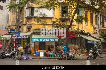 La tradizionale Hoa Đào, o fiori di pesca, e altre prelibatezze del capodanno lunare, vengono confezionate e vendute in un angolo di strada nel centro storico di Hanoi, Vietnam. Foto Stock