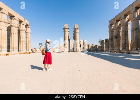 Il viaggiatore felice di donna esplora le rovine dell'antico tempio di Karnak nella città patrimonio di Luxor in Egitto. Gigantesca fila di colonne con gerogliera scolpita Foto Stock