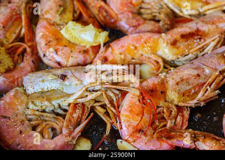 Langoustine sulla padella con burro, limone e aglio. Grandi gamberetti alla griglia, langoustini cotti in una padella con spezie, erbe e limone. Foto Stock