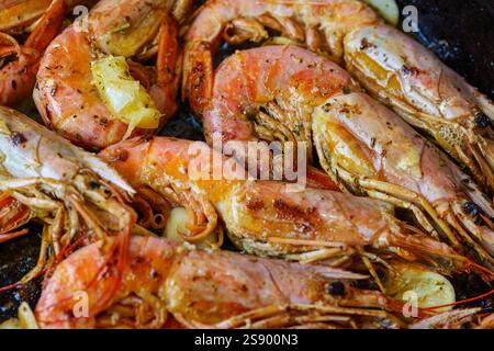 Langoustine sulla padella con burro, limone e aglio. Grandi gamberetti alla griglia, langoustini cotti in una padella con spezie, erbe e limone. Foto Stock