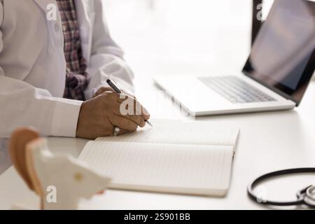 Primo piano tagliato medico maschio scrivere a mano alla scrivania Foto Stock