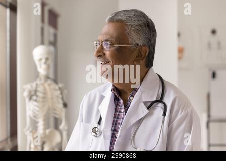 Buon vecchio medico di sesso maschile che guarda la finestra all'ufficio della clinica Foto Stock