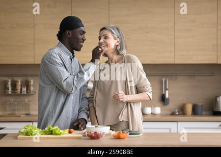 Affettuoso marito africano cuocere il cibo con matura moglie europea Foto Stock