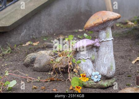 Due funghi decorativi posti a terra con un piccolo fiore blu che cresce tra di loro. Foto Stock