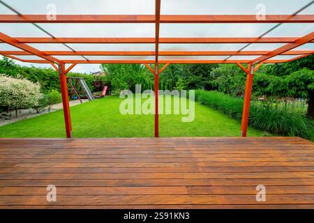 Pergola in legno con tetto in policarbonato trasparente che copre un ponte giardino in un cortile moderno Foto Stock