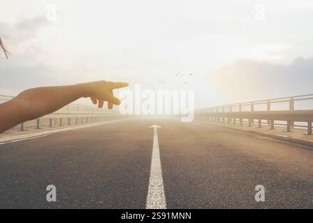 Persona che punta verso il tramonto sulla strada deserta con l'ambiente Center Arrow Foto Stock
