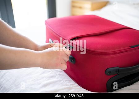 Mano di una giovane donna che chiude la valigia rossa. Foto Stock