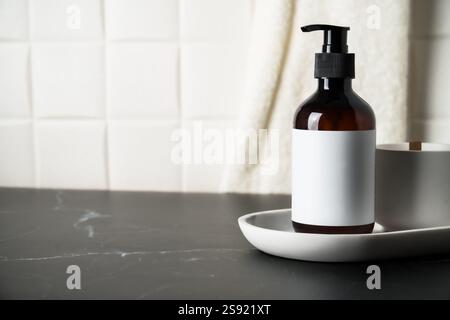 Shampoo in bottiglia con tiralatte su sfondo bianco e asciugamani. Foto Stock