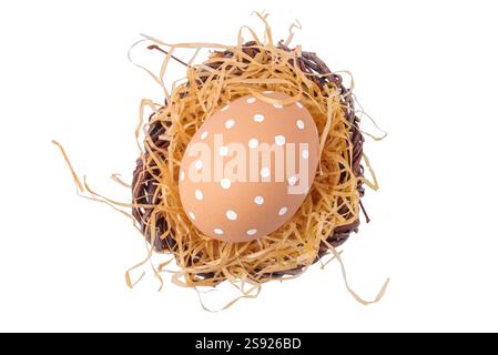 Un uovo di Pasqua con ornamento bianco in un nido con paglia isolata su fondo bianco Foto Stock