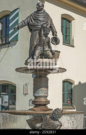 Fontana sulla piazza del mercato di fronte al vecchio municipio, ora biblioteca comunale, Holzkirchen, alta Baviera, Baviera, Germania, Europa Foto Stock