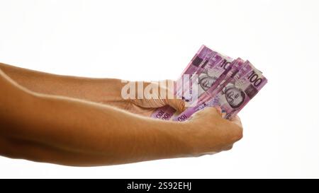 Uomo che tiene in mano più banconote del peso filippino su uno sfondo bianco isolato con dettagli visibili Foto Stock
