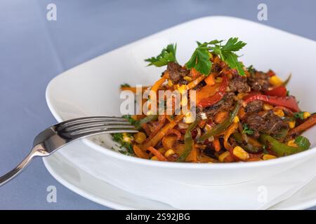 Strisce sfrigolanti di manzo con peperoni rossi e fajitas di peperoni verdi con prezzemolo, manzo di Pechino, mais e cibo di strada Foto Stock