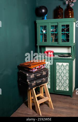 armadietto verde con telefono rosso e valigie retrò. zona foto in studio fotografico Foto Stock