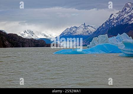 Vista lontana del Ghiacciaio Grigio che scorre nel Lago Grey circondato dalle montagne di Torres del Paine durante il giorno Foto Stock