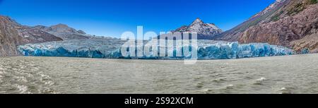 Vista lontana del Ghiacciaio Grigio che scorre nel Lago Grey circondato dalle montagne di Torres del Paine durante il giorno Foto Stock