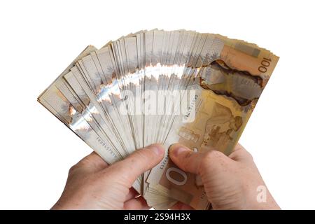 Le mani di una persona in primo piano hanno una grossa somma di denaro canadese, cento banconote da 100 dollari in una fessura isolata su bianco Foto Stock