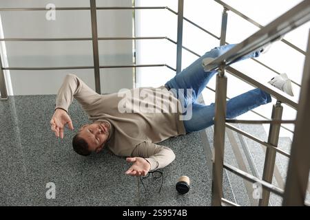 Uomo ferito sulle scale dell'edificio dopo la caduta. Incidente pericoloso Foto Stock