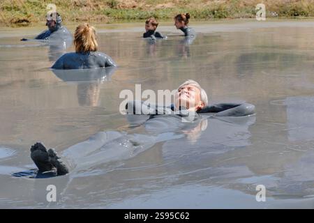 Anapa, Russia - 1° settembre 2024: Serena scena di persone che si godono il bagno termale naturale di fango in un ambiente all'aperto. Donna anziana che galleggia in fango ricco di minerali, Foto Stock