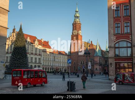 Piazza del mercato di Breslavia a gennaio con un albero di Natale, il municipio storico, edifici colorati, decorazioni festose e persone che camminano su ciottoli Foto Stock