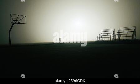 Scena notturna Foggy al Poush Mela Ground, Santiniketan, Bengala Occidentale, India, con una figura solitaria, canestro e candeggianti vuoti Foto Stock