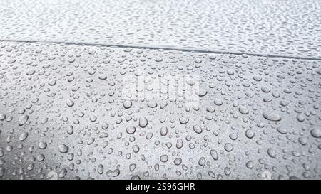 Primo piano di gocce di pioggia sulla superficie di un'auto, gocce d'acqua che formano uno schema su vernice metallica" Foto Stock