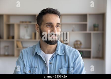 Attento uomo ispanico con camicia casual in denim in posa al chiuso Foto Stock