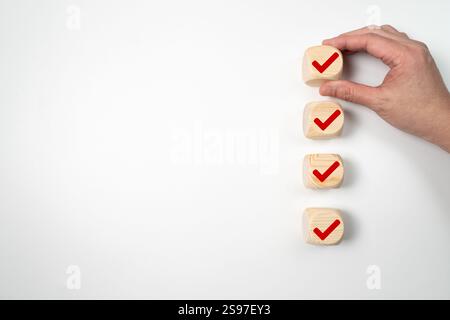 Mano messo giù il cubo di legno di segno di spunta rosso per elenco di controllo o elenco delle attività Foto Stock