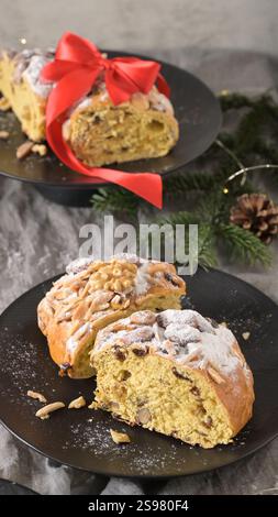 Due fette di Bolo Rainha, un tradizionale pane dolce portoghese, adornato con mandorle e noci, spolverato con zucchero a velo e legato con una costoletta rossa Foto Stock