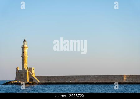 Chania - Creta - 16 agosto 2024; una persona insignificante sullo storico faro veneziano alla fine della lunga frangiflutti che protegge il porto di Chania in C Foto Stock