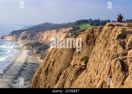 Una coppia si trova su una scogliera che si affaccia sull'oceano. La scena è tranquilla e serena, con il suono delle onde che si infrangono sullo sfondo. Il coupl Foto Stock