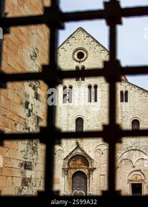 La facciata della chiesa di San Nicola a Bari vista attraverso una finestra con griglie metalliche Foto Stock
