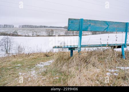 panchina su una collina che si affaccia sul lago e sui campi in inverno. Foto di alta qualità Foto Stock