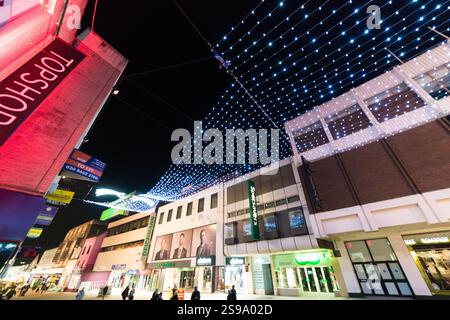 Luci natalizie disposte di fronte a una strada nel centro della città di Bromley, Regno Unito, sopra negozi come Topshop, Deichmann, Specsavers e Next. Foto Stock