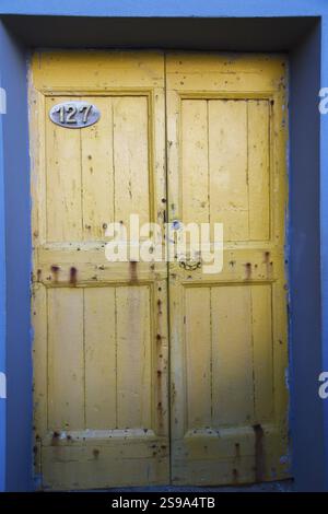 Primo piano di porte d'ingresso in legno dipinto di giallo su facciata residenziale rivestita in stucco blu, Riomaggiore, cinque Terre, provincia di la Spezia Foto Stock