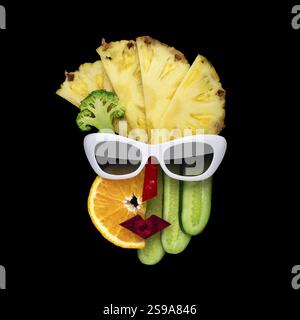 Foto creativa di un volto femminile in stile cubista con occhiali da sole fatti di frutta e verdura, su sfondo nero Foto Stock