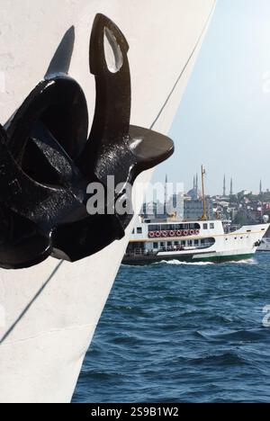 Scena marittima a Istanbul che mostra l'ancora di una nave in primo piano con un traghetto che attraversa il Bosforo e lo skyline storico, tra cui l'iconico mi Foto Stock