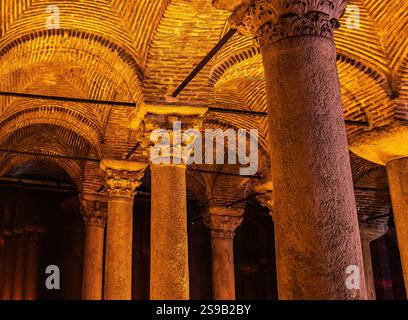 Una vista di un'antica sala sotterranea con colonne, drammaticamente illuminata da una calda illuminazione, che mostra la sua ricca storia e l'eleganza architettonica Foto Stock