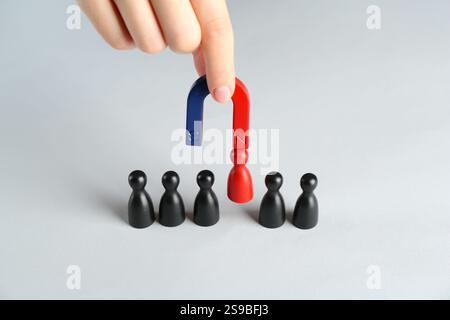Donna con magnete che attrae pezzi rossi tra quelli neri al tavolo bianco, primo piano Foto Stock