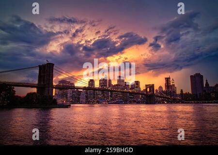 L'iconico Ponte di Brooklyn attraversa con grazia l'East River, collegando lo storico quartiere di Brooklyn allo scintillante skyline di Lower Manhattan. Foto Stock
