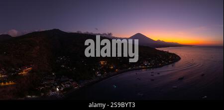 Giro panoramico in droni della costa con il vulcano e tramonto al crepuscolo con mare tranquillo a Bali. Foto Stock